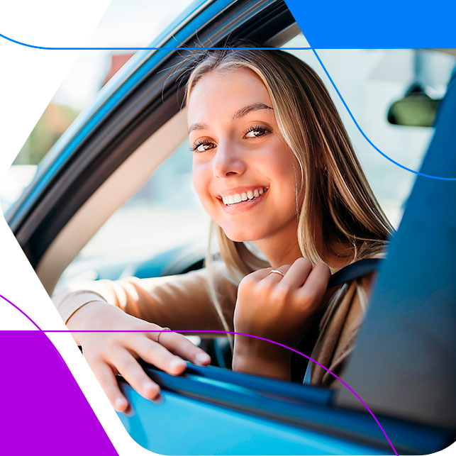 Foto de uma mulher jovem sorrindo, olhando pela janela do carro que est digirindo